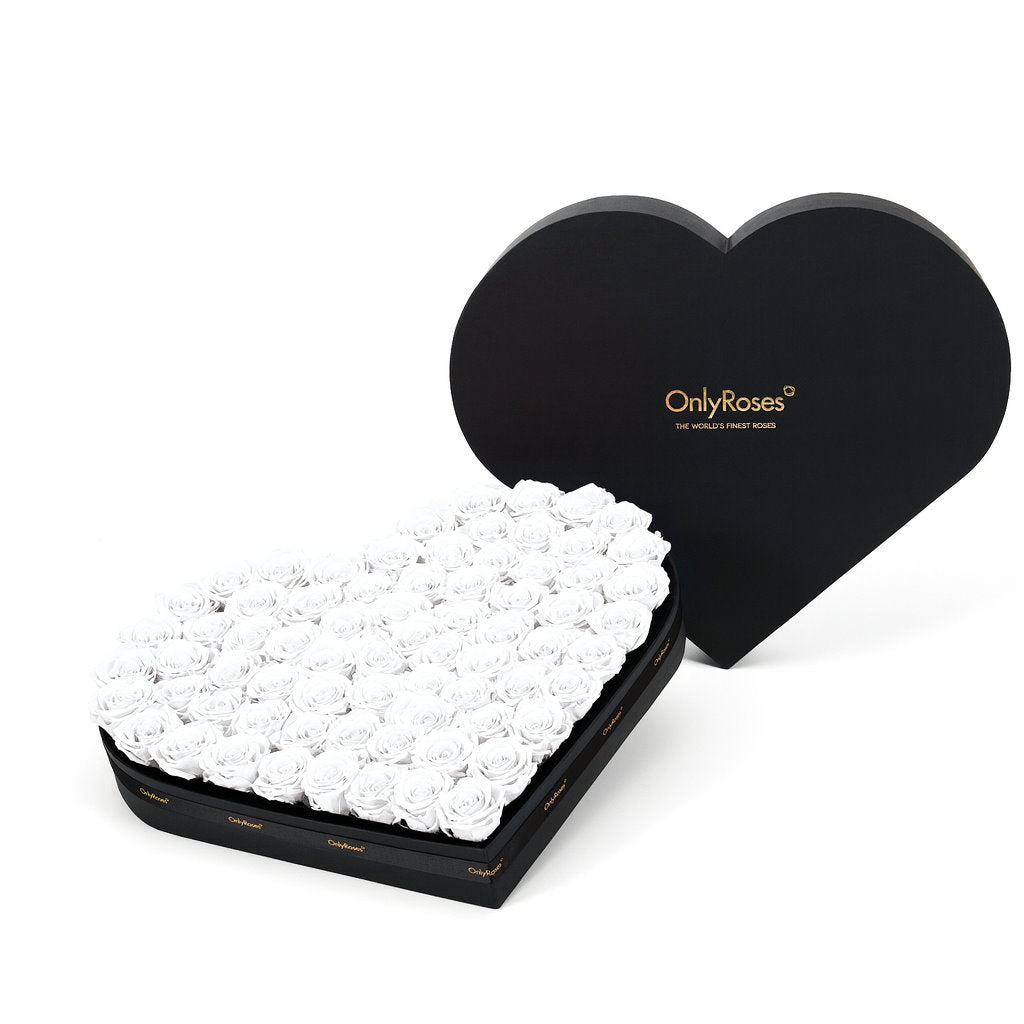 Heart-shaped box filled with white roses and branded lid on a white background