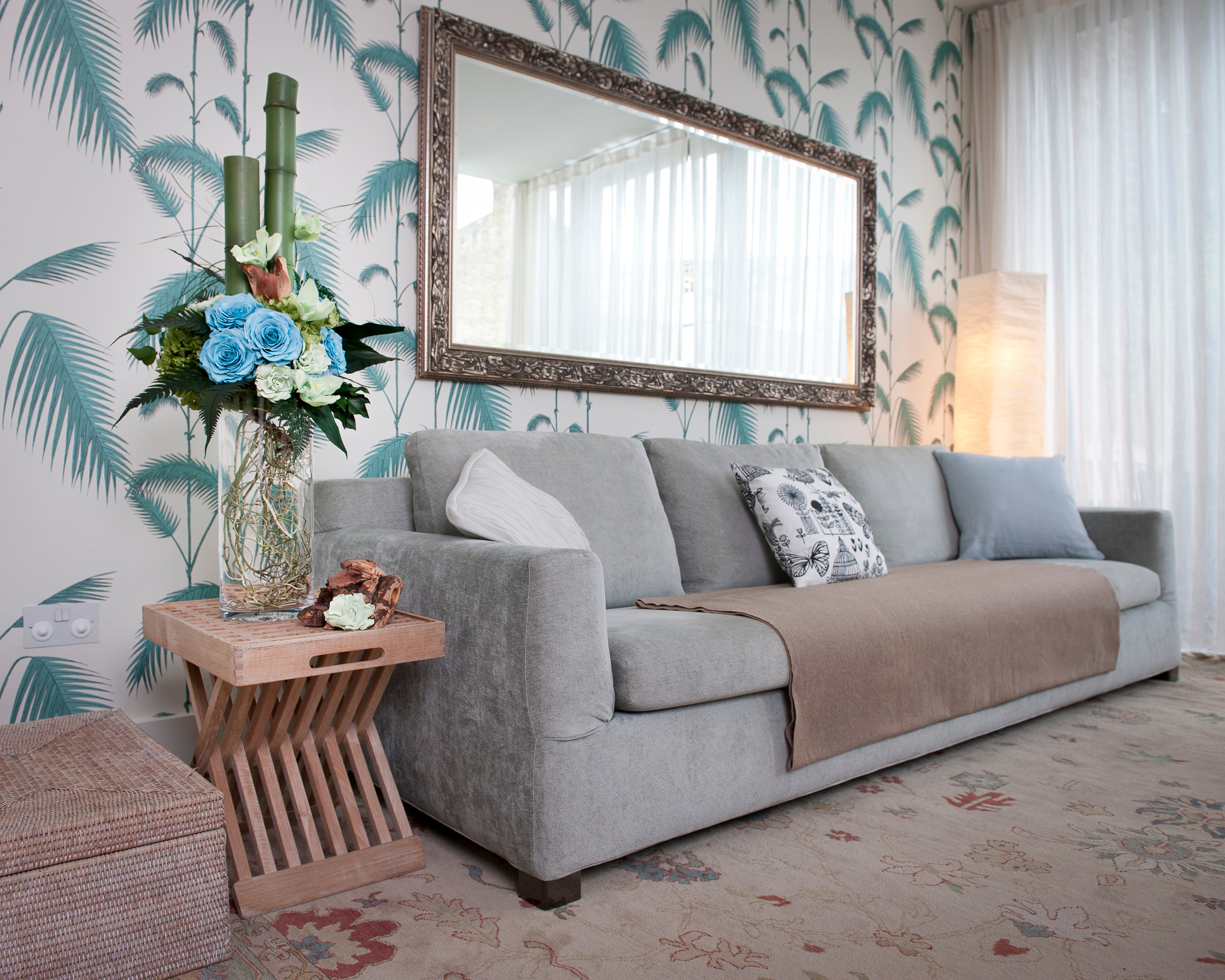 Living room with gray sofa, floral arrangement, and decorative mirror.