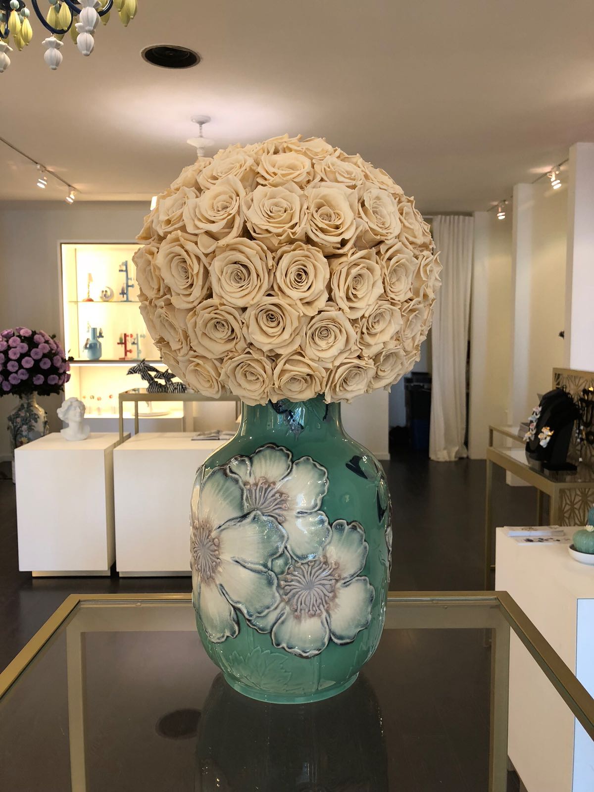 Decorative vase with a large bouquet of beige roses in a modern interior setting.