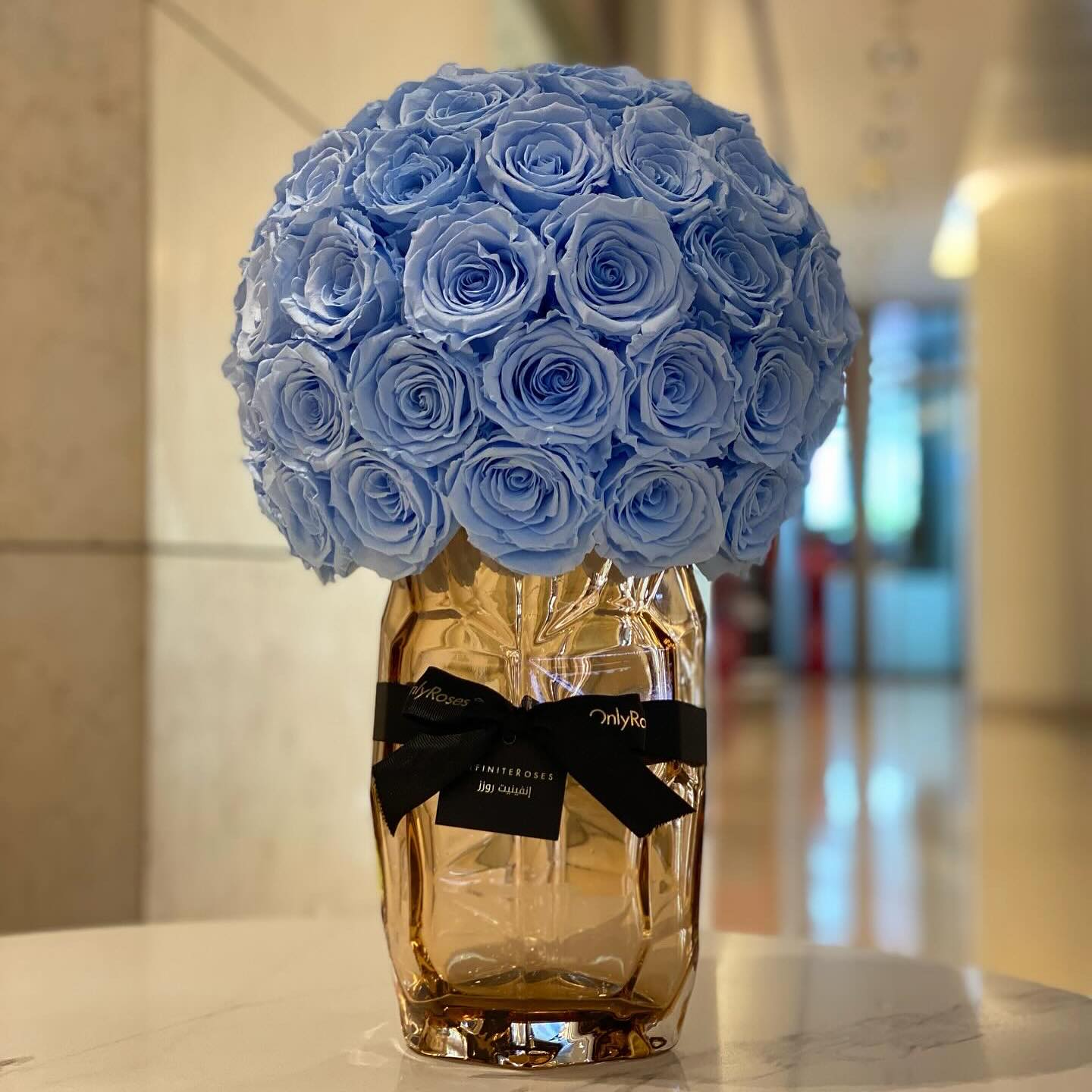Bouquet of blue roses in a glass vase with a brand label on a blurred background