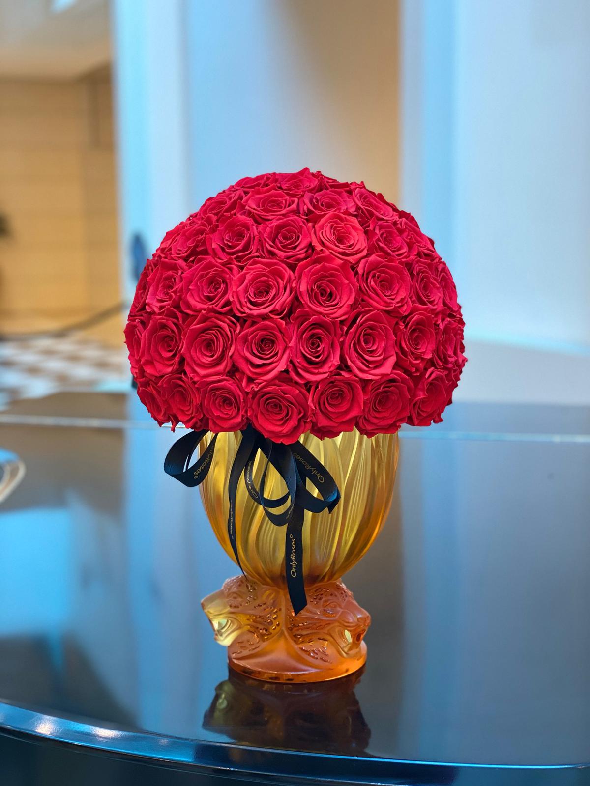 Bouquet of red roses in a yellow vase on a reflective surface