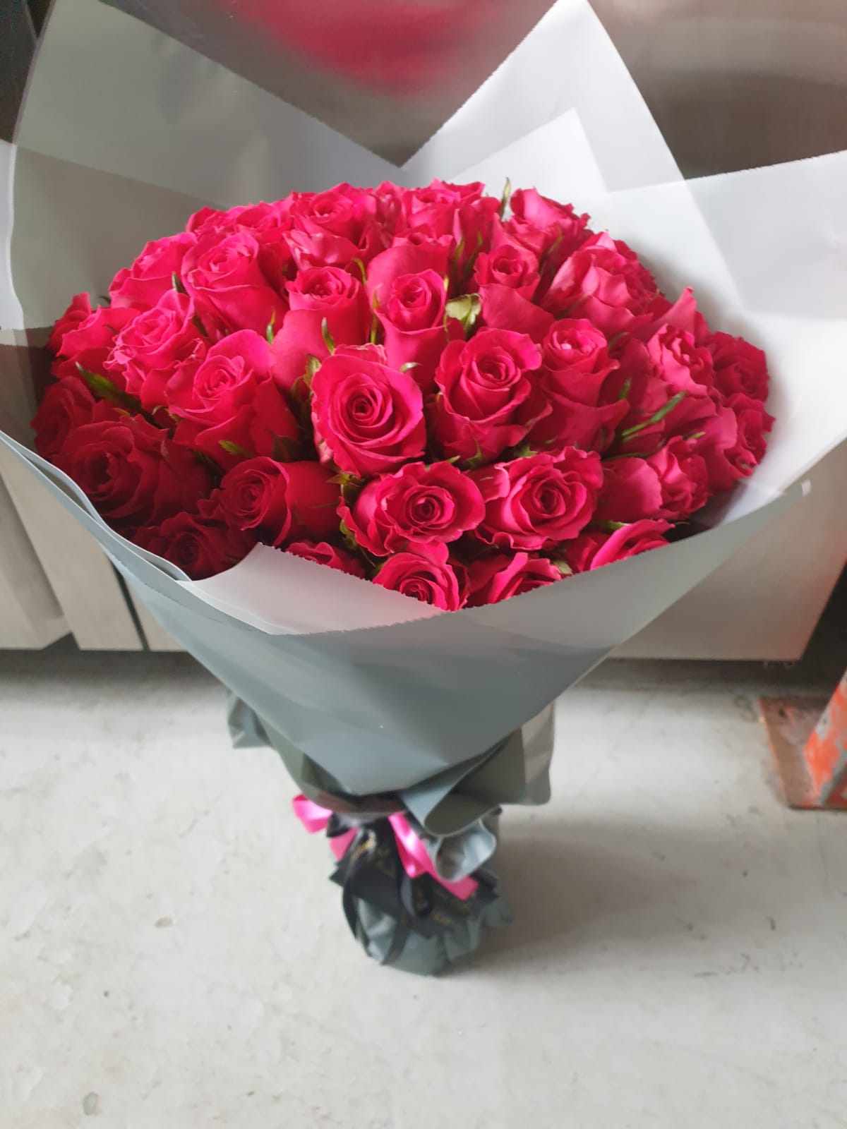 Bouquet of red roses wrapped in gray paper on a light background