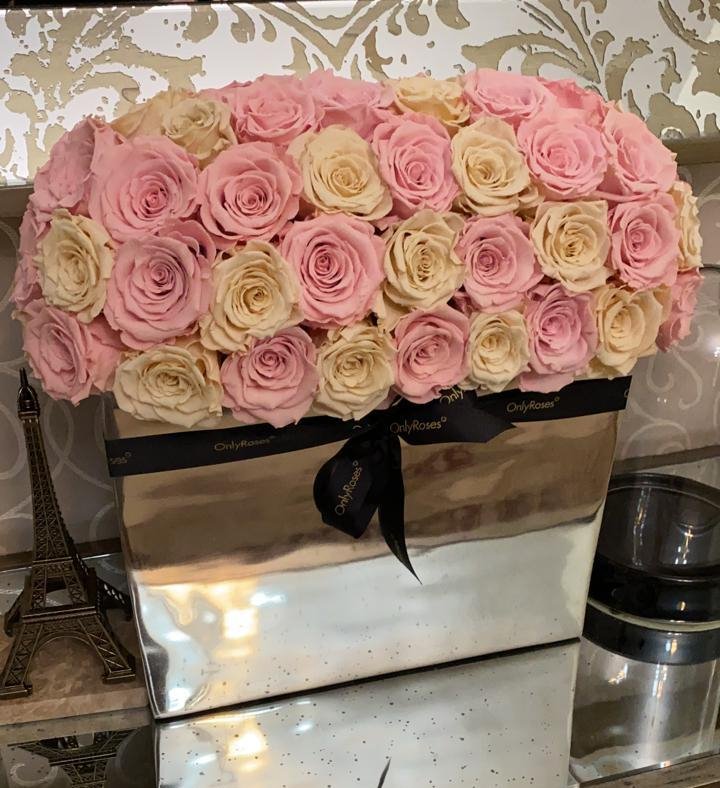 Box of pink and white roses with a visible brand name on a decorative background