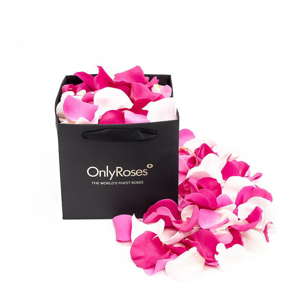 Black 'Only Roses' bag filled with pink and white rose petals on a white background