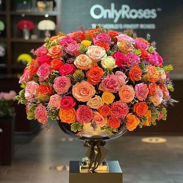 Bouquet of colorful roses in a decorative vase with 'OnlyRoses' branding in the background.