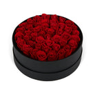 Black round box filled with red roses on a white background