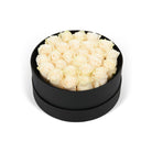 Black round box filled with white roses on a white background