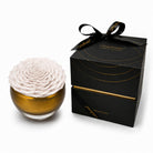 White rose in a glass bowl with a black gift box featuring a bow, on a white background.