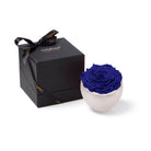 Blue rose in a white vase next to a black gift box with 'Only Roses' branding on a white background