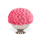 Spherical arrangement of pink roses on a white pedestal against a white background