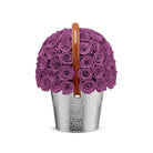 Silver bucket filled with purple roses on a white background