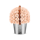 Bouquet of peach roses in a silver metal container with a brown handle on a white background