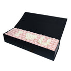 Black box filled with pink and white roses on a white background
