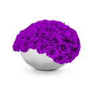 White spherical vase filled with purple roses on a white background