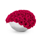 White spherical vase filled with bright pink roses on a white background