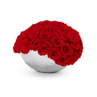 White spherical vase filled with red roses on a white background
