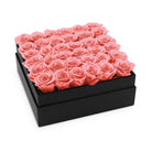 Black box filled with pink roses on a white background