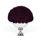 Bouquet of dark purple roses on a white pedestal against a white background