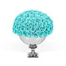 Bouquet of turquoise roses in a silver vase on a white background