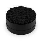 Black round box filled with black roses on a white background
