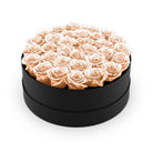 Round black box filled with peach roses on a white background