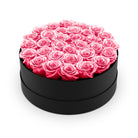 Black round box filled with pink roses on a white background