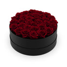 Black round box filled with red roses on a white background