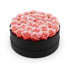 Round black box filled with pink roses on a white background