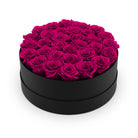 Black round box filled with pink roses on a white background