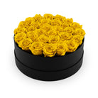 Round black box filled with yellow roses on a white background