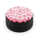 Round black box filled with pink roses on a white background