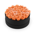 Black round box filled with orange roses on a white background