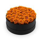 Black round box filled with orange roses on a white background