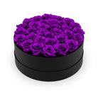 Heart-shaped box filled with purple roses on a white background
