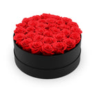 Black round box filled with red roses on a white background