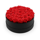 Black round box filled with red roses on a white background