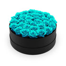 Heart-shaped box filled with turquoise roses on a white background
