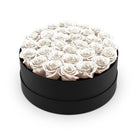 Black round box filled with white roses on a white background