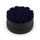 Black round box filled with dark blue roses on a white background