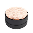 Black round box filled with pink roses on a white background
