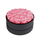Black round box filled with pink roses on a white background