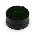 Black round box filled with dark green roses on a white background
