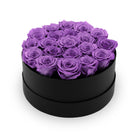 Black round box filled with purple roses on a white background
