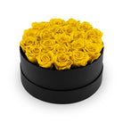Black round box filled with yellow roses on a white background