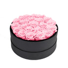 Black round box filled with pink roses on a white background