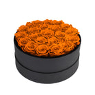 Black round box filled with orange roses on a white background