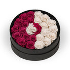 Round black box with pink and white roses arranged in a yin yang design on a white background