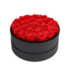 Black round box filled with red roses on a white background