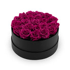 Black round box filled with pink roses on a white background