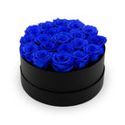 Black round box filled with blue roses on a white background